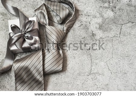 Happy father's Day. Gift box and tie on a gray concrete background. Copy space, flat lay. Greeting card.