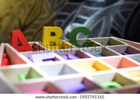 Colourfull Wooden Alphabet on A Wooden Organiser Box With Orange Background