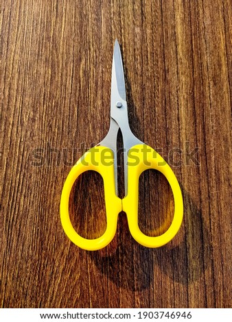 Yellow colored scissors on wooden plank.
