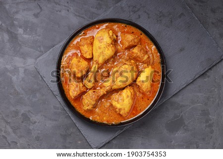 Chicken curry or masala,Kerala style chicken curry using fried coconut in traditional way and arranged in a black  ceramic vessel which is placed on a graphite sheet with grey background,isolated. Royalty-Free Stock Photo #1903754353