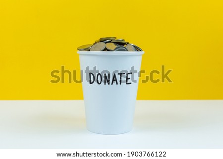 Donate text on white cup with yellow background.