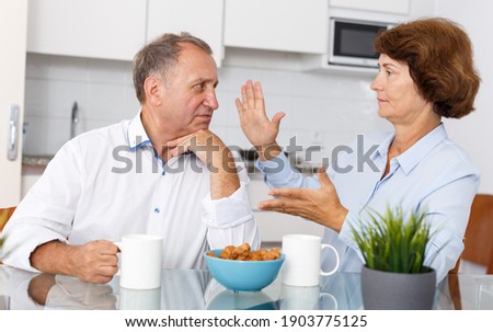 Portrait of sad mature couple discussing, quarrel at home kitchen indoor