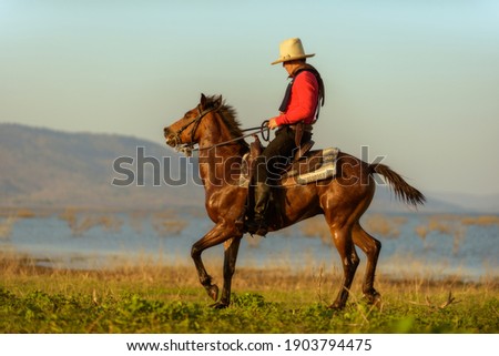 Western cowboys riding horses along the river.