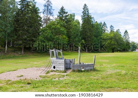 View of natural landscape with abandoned wooden play ship on green forest trees background. Sweden. 