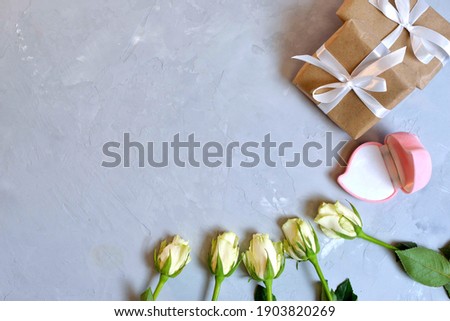 pink blank box for gold jewelry as a gift on a gray background with white roses. The moment of a wedding, anniversary, engagement, or Valentine's Day. Happy day