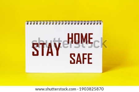 Words Stay Home Stay Safe written on notepad and yellow background. Self Quarantine at Home Concept Staying at home during a pandemic