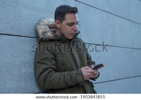 man in coat using mobile phone