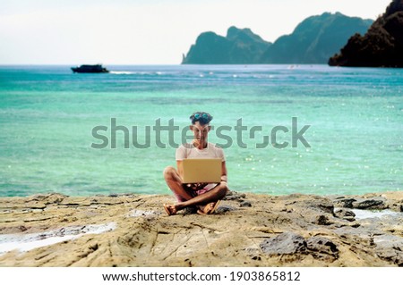 a digital nomad asian man working by the tropical sea with his laptop Royalty-Free Stock Photo #1903865812