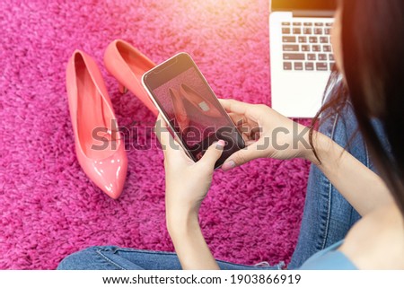 selling online idea concept. online seller use mobile phone take a photo of high heels shoe for upload to online shopping store website.