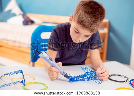 The child plays with a 3D pen. The boy creates a 3D toy with a pen.