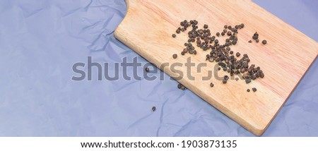 Black pepper peas on a wooden cutting board, top view, spices, banner.