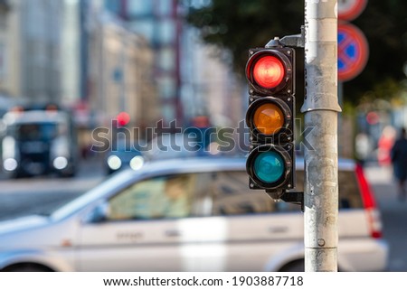 blurred view of city traffic with traffic lights, in the foreground a traffic light with a red light Royalty-Free Stock Photo #1903887718
