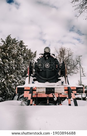 Beautiful image of an old locomotive in the nature with some snow on it. Concept of background of a snowy day. Vertical picture