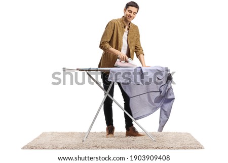 Cheerful young man ironing a shirt isolated on white background