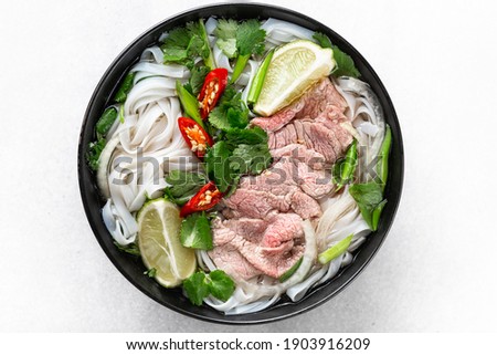 Pho Bo vietnamese soup with beef and rice noodles on a white background, top view, close-up Royalty-Free Stock Photo #1903916209