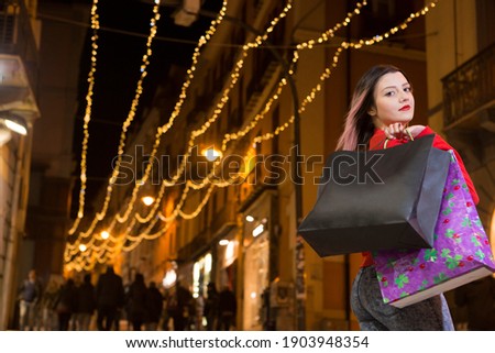 Beautiful woman with brown hair painted in violets, dressed in jeans and a red sweater, goes around the city at nigh