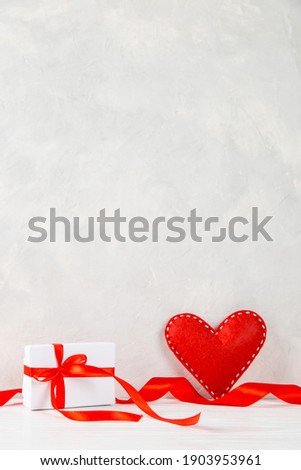Red heart, gift, ribbon against the background of a white wall, concept, a postcard for Valentine's Day. Copy space.