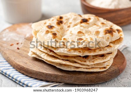 Homemade Roti Chapati Flatbread  on a wooden board close-up. Freshly baked indian flatbread Royalty-Free Stock Photo #1903968247