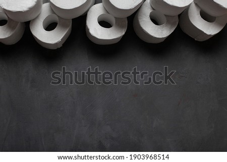 Toilet paper roll on dark concrete surface with empty space for your text. White toilet paper. Top view. 