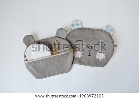 Cute handmade bear pouch, makeup remover discs and golden hair pins over white