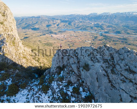 IMAGE OF AN ATHLETE TRAIL RUNNER IN A MOUNTAIN. A PERSON HIKING AT THE TOP OF A MOUNTAIN. RUNNER ON EDGE OF CLIFF. SPORT AND OUTDOOR CONCEPT.
