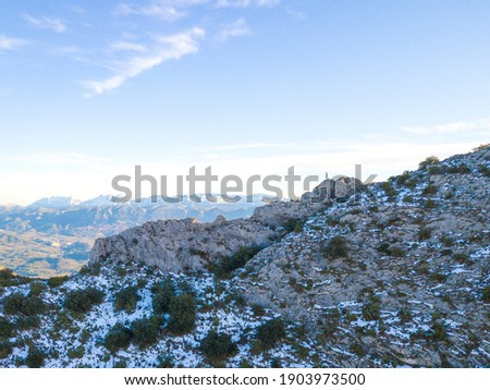 IMAGE OF AN ATHLETE TRAIL RUNNER IN A MOUNTAIN WITH SNOW. A PERSON HIKING AT THE TOP OF A MOUNTAIN. RUNNER ON EDGE OF CLIFF. SPORT AND OUTDOOR CONCEPT.