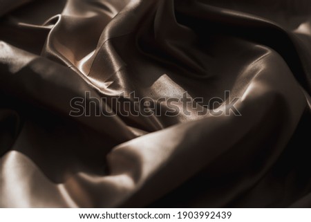 Brown atlas or silk fabric background, texture. Top view.
