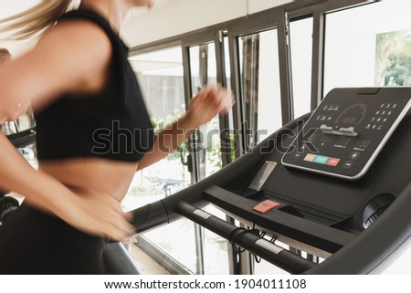 Young athletic woman running on treadmill during fitness workout. Long exposure for motion blur.