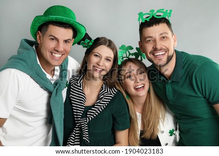 Happy people in St Patrick's Day outfits on light grey background