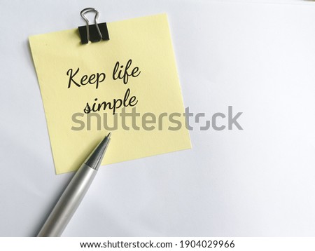 Top view Text of KEEP LIFE SIMPLE write on sticky note with paper clips and pen. isolated on white background 