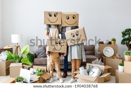 concept of moving to a new apartment and a mortgage. Unrecognizable couple and kids wearing carton boxes on heads standing together in new flat with various stuff during relocation Royalty-Free Stock Photo #1904038768