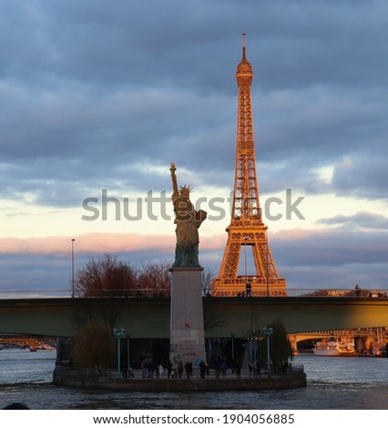 Sunset view of both The Eiffel Tower and The Statue of Liberty in Paris while having an open-air tour of the City of Light from along the River seine . France.