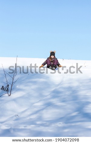 A cute ten years old teenage girl having fun on snow tube on a winter day. Wintertime, entertainment, activity, childhood, holidays concept.