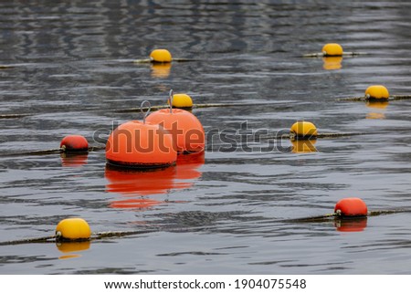 A buoy is a floating device that can have many purposes, Selective focus of yellow and orange round buoy with rope above the surface, Water background.