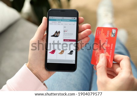 Woman with credit card using smartphone for online shopping indoors, closeup