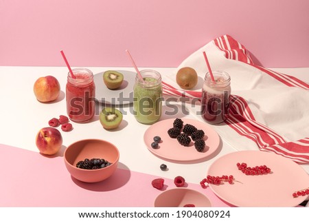 Summer colorful fruit smoothies in jars and plates with fruits and berries on pink background. Healthy, detox and diet food concept. Modern still life. Food photography. Copy space