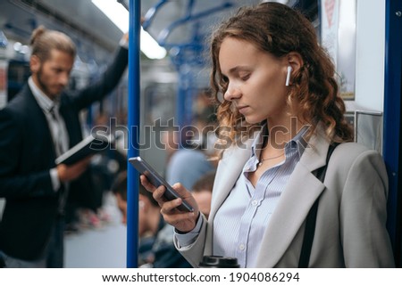 young woman using her smartphone on subway train. Royalty-Free Stock Photo #1904086294