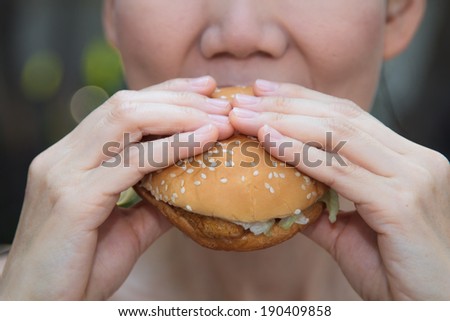 Asian girl eating a hamburger in a swimsuit.