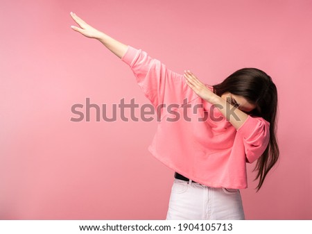 Photo of attractive woman in glasses shows gesture dab, wear casual pink t-shirt white pants isolated pink color background