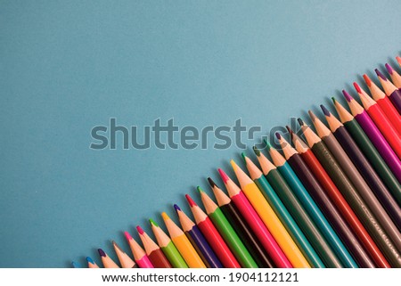 Close-Up Of colored pencils placed on blue paper background with copy space for your image or text