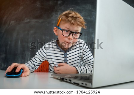 Little kid boy programming with laptop computer. Close up of the portrait of pupil in blue light blocking glasses. Child codding. Computer vision syndrome. Online education. IT lessons. Royalty-Free Stock Photo #1904125924