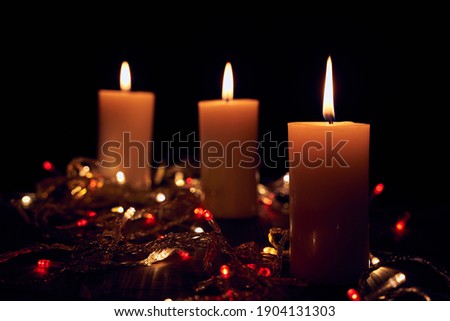 Flame candles with decorative lights on black table background