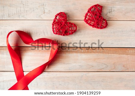Red silk ribbon in shape of heart on wooden background. Valentine's day concept. Place for text.