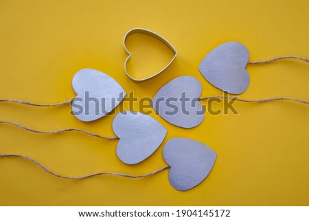 silver hearts on ropes with a heart shape on a yellow background