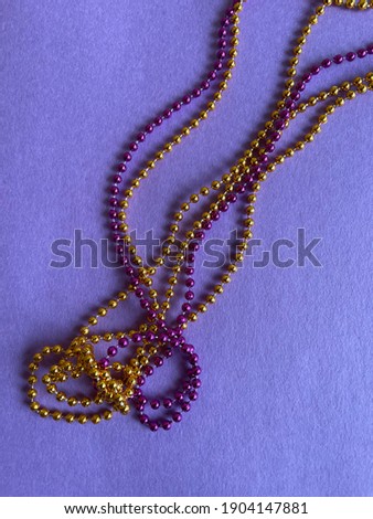 Colorful Mardi Gras beads on purple background
