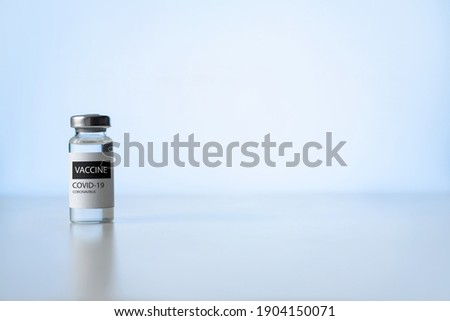 Ampoule of covid-19 vaccine on a laboratory table. Cure for coronavirus, fight against pandemic. Light blue background, copy space. Vaccination concept. Royalty-Free Stock Photo #1904150071