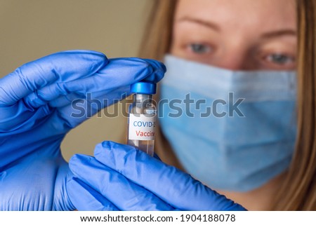 Woman doctor holding vaccine or medicine in transparent glass on her hand.