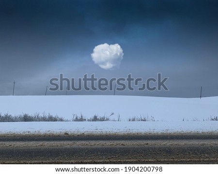 Beautiful snowy landscape with dark blue sky. A huge field with big white cloud electric poles. Winter background with copy space. Good New Year spirit.