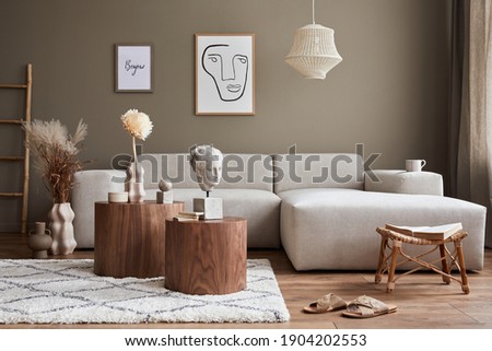 Interior design of stylish living room with modern neutral sofa, mock up poster farmes, dried flowers in vase, coffee tables, decoration and elegant personal accessories in home decor. Template.