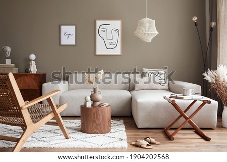 Stylish interior with design neutral modular sofa, mock up poster frames,  rattan armchair, coffee tables, dried flowers in vase,  decoration and elegant personal accessories in modern home decor. 